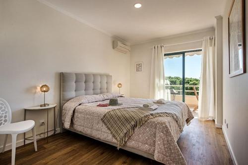 a white bedroom with a large bed and a window at Casa dos Salgados in Guia