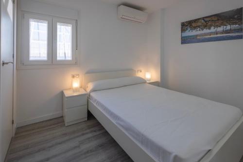 een witte slaapkamer met een wit bed en 2 lampen bij El mirador del Mentidero in Cádiz