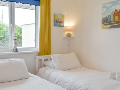 two beds in a room with two windows at Beach Cottage in Benllech