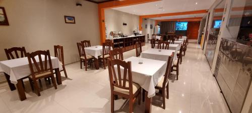 un restaurante con mesas y sillas blancas y un bar en Ensenada Hotel, en San Juan