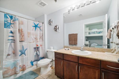 y baño con lavabo, aseo y cortina de ducha. en Spacious Resort Condo with Breathtaking Gulf Views! by Dolce Vita Getaways PCB, en Panama City Beach