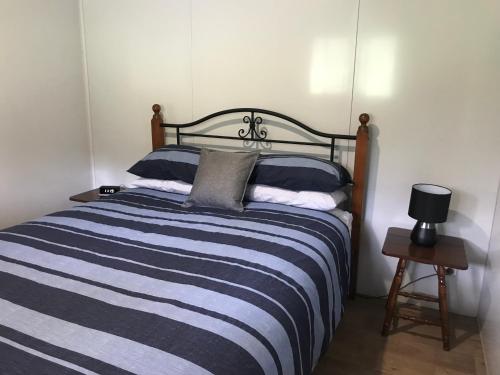1 dormitorio con 1 cama con rayas azules y blancas en BIKABISA en Paterson