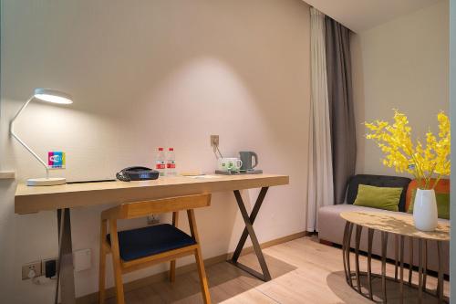 a room with a desk with a chair and a couch at Ibis Styles XM Zhongshan Hotel in Xiamen