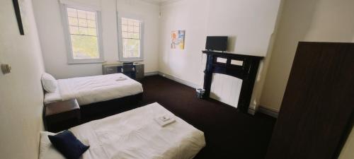 Kleines Zimmer mit 2 Betten und einem Tisch in der Unterkunft Leura Hotel in Camperdown