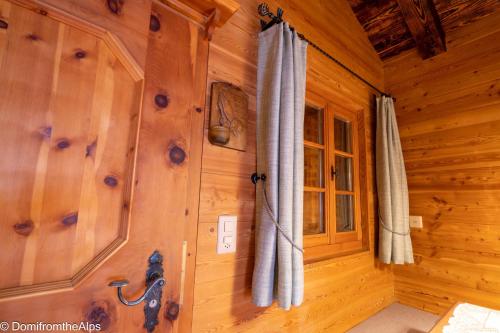 a room with wooden walls and curtains in a cabin at Haus Zer Trächu in Saas-Almagell