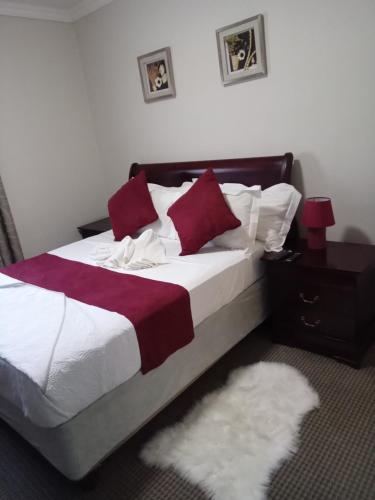 a bedroom with a large bed with red and white pillows at Antique Home BnB in Gaborone