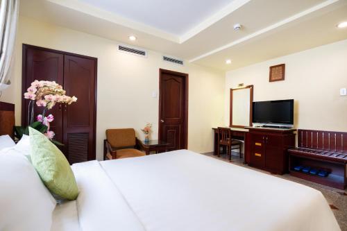 a bedroom with a bed and a desk and a television at LUCASTA SAIGON Hotel in Ho Chi Minh City