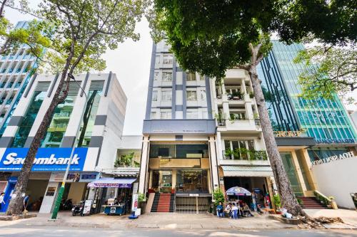 a building in the middle of a street with trees at LUCASTA SAIGON Hotel in Ho Chi Minh City