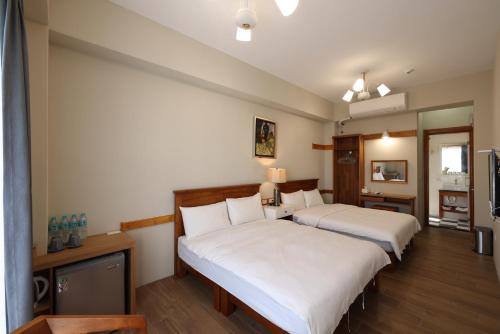 2 bedden in een hotelkamer met witte lakens bij Looksea in Hualien