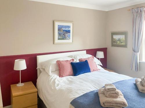 um quarto com uma cama branca com almofadas vermelhas e azuis em The Loft em Warkworth