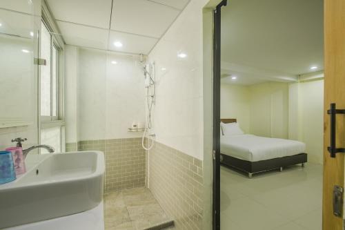 a bathroom with a shower and a sink and a bed at Petchsiri Room เพชรสิริรูม in Ban Chuat Plai Mai
