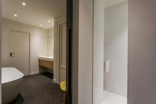 łazienka z białą wanną i umywalką w obiekcie Appartement design au coeur de Rennes w mieście Rennes