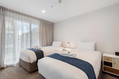 two beds in a room with a window at FERNZ Motel & Apartments Birkenhead in Auckland