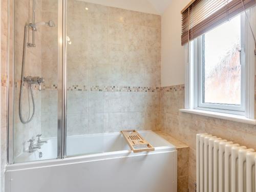 a bathroom with a bath tub and a window at Hill House in Sholden