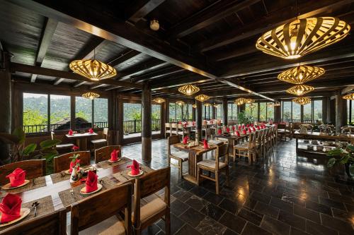 a restaurant with wooden tables and chairs and chandeliers at Sin Chai Ecolodge in Sa Pa