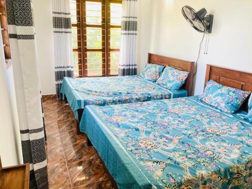 una camera con 2 letti, lenzuola blu e ventilatore di Sensitha Holiday home a Anuradhapura