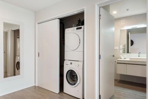a white laundry room with a washer and dryer at FERNZ Motel & Apartments Birkenhead in Auckland