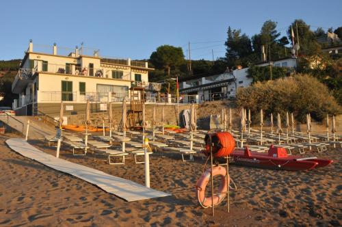 a beach with a bunch of chairs and a building at Appartamenti Villa Miramare in Capoliveri