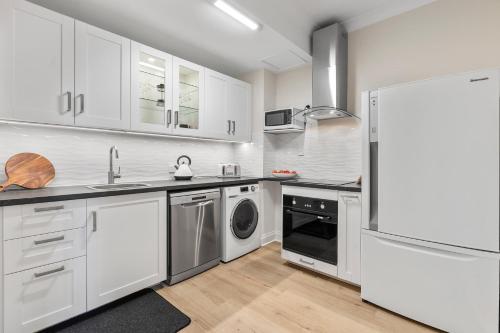 a kitchen with white cabinets and a washer and dryer at Cadell Street Apartments Goolwa in Goolwa