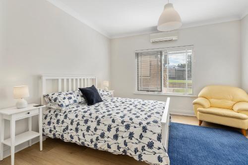 a bedroom with a bed and a yellow chair at Cadell Street Apartments Goolwa in Goolwa