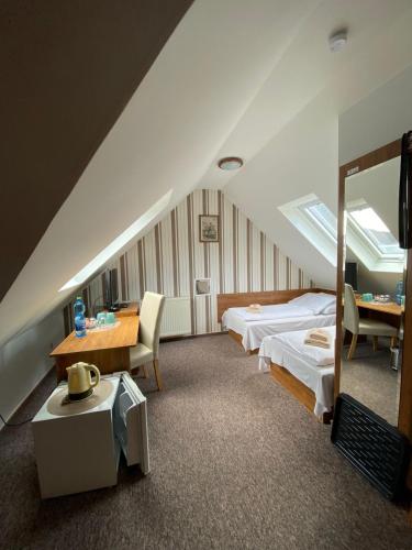 a bedroom with two beds and a table and a mirror at Penzión Tiberia in Trenčín