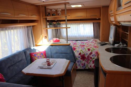 ein Wohnzimmer mit einem Sofa und einem Bett in einem Wohnwagen in der Unterkunft Caravan 't Koekoeksnest in Aagtekerke