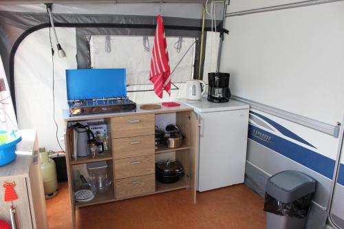 a kitchen with a stove and a refrigerator in a tent at Caravan 't Koekoeksnest in Aagtekerke