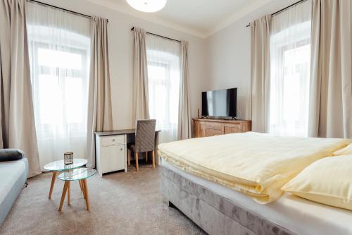 1 dormitorio con 1 cama, TV y sofá en Botanický dvor en Banská Štiavnica