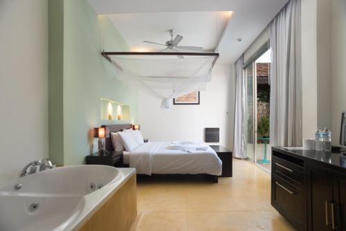 a bedroom with a bed and a bath tub and a sink at Mandalai Hotel in Chaloklum
