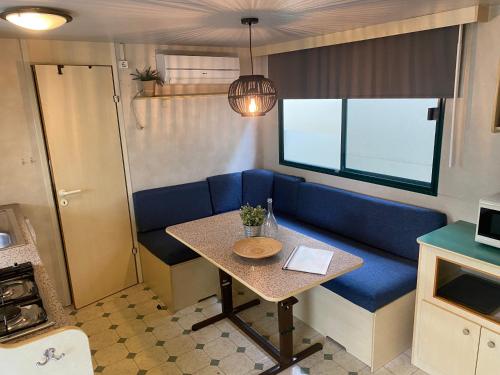 a small dining room with a blue couch and a table at Comfortabele familie chalets met veranda incl airco dichtbij zee! in Viareggio