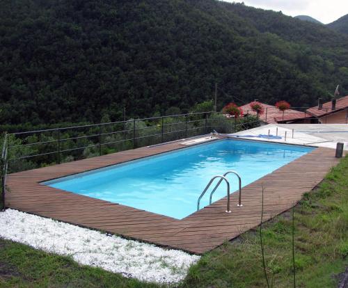 a swimming pool with a wooden deck next to a mountain at Agriturismo Il Giglio e la Rosa in Montale