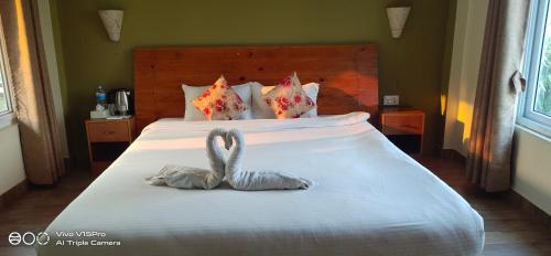 two swans towels sitting on top of a bed at Hotel hornbill in Sauraha