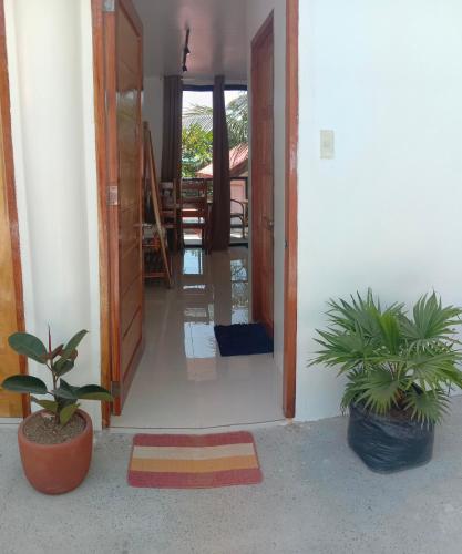 a hallway with two potted plants and an open door at Corong Beach Resort in El Nido