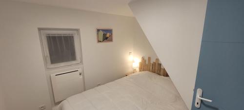 een kleine witte slaapkamer met een bed en een raam bij Appartement 5 personnes à 100 m de la plage in Berck-sur-Mer