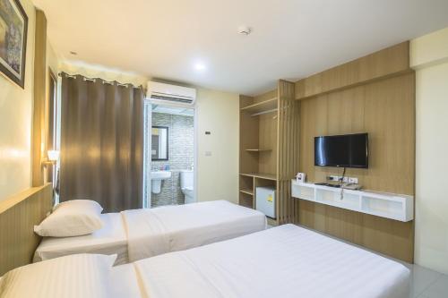 a hotel room with two beds and a tv at Petchsiri Room เพชรสิริรูม in Ban Chuat Plai Mai