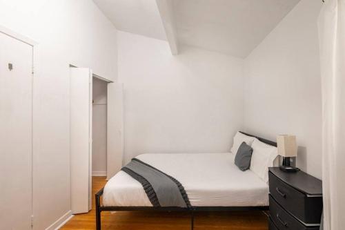 a white bedroom with a bed and a black dresser at Harmony Home Near University of Waterloo in Waterloo