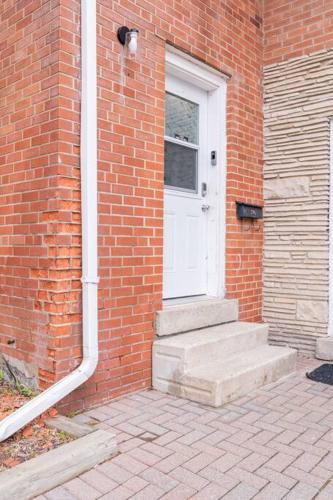 a brick house with a white door and stairs at Harmony Home Near University of Waterloo in Waterloo