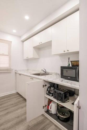 a white kitchen with white cabinets and a microwave at Harmony Home Near University of Waterloo in Waterloo