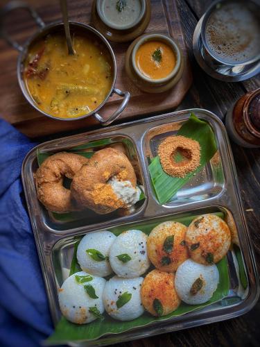 a tray of food with dip and donuts and dipping sauce at Willo stays The Metro Landsend Beach Resorts in Kannur