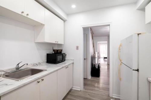 a white kitchen with a sink and a refrigerator at Harmony Home Near University of Waterloo in Waterloo