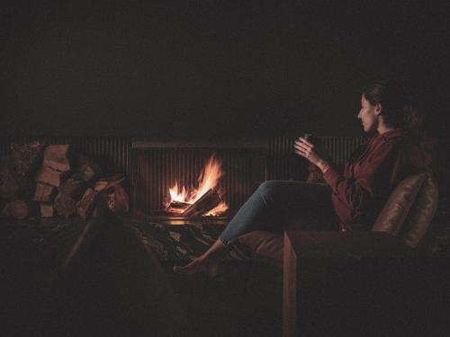 a woman sitting on a couch in front of a fire at Hotel Pepe Vieira in Raxo