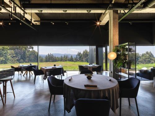 a restaurant with tables and chairs and a large window at Hotel Pepe Vieira in Raxo
