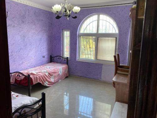 a purple bedroom with two beds and a window at stay baitlahem in Bayt Jālā