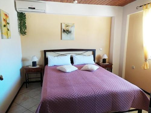 - une chambre avec un lit et une couette violette dans l'établissement Aspri Villa, à Ammoudia