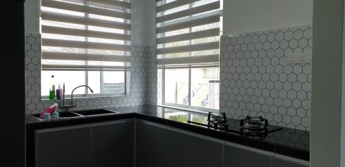 a kitchen with a sink and a window at El Manzil Homestay with Pool in Guar Chempedak