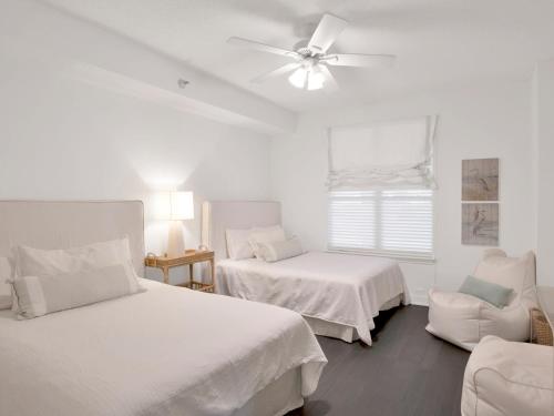 a white bedroom with two beds and a ceiling fan at Beach Colony Towers #2B - Villa Monarch in Perdido Key