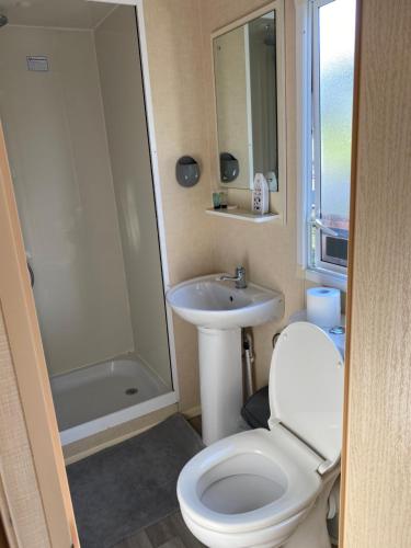 a bathroom with a toilet and a sink and a shower at 14 Greenwood Thorness Bay in Porchfield