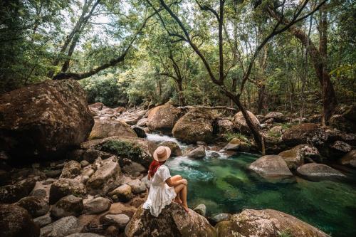 a woman sitting on a rock by a river at 604 Chic City Apartment with Water Views in Cairns