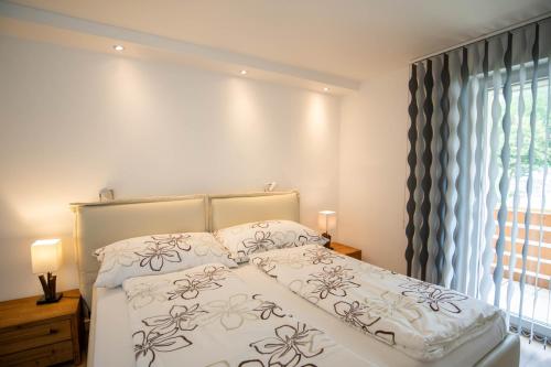 a bedroom with a bed with white sheets and a window at Haus Cristal - 1441m in Leukerbad