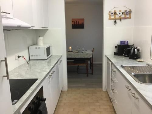 a kitchen with white cabinets and a sink and a table at Camelot 18 in Forster